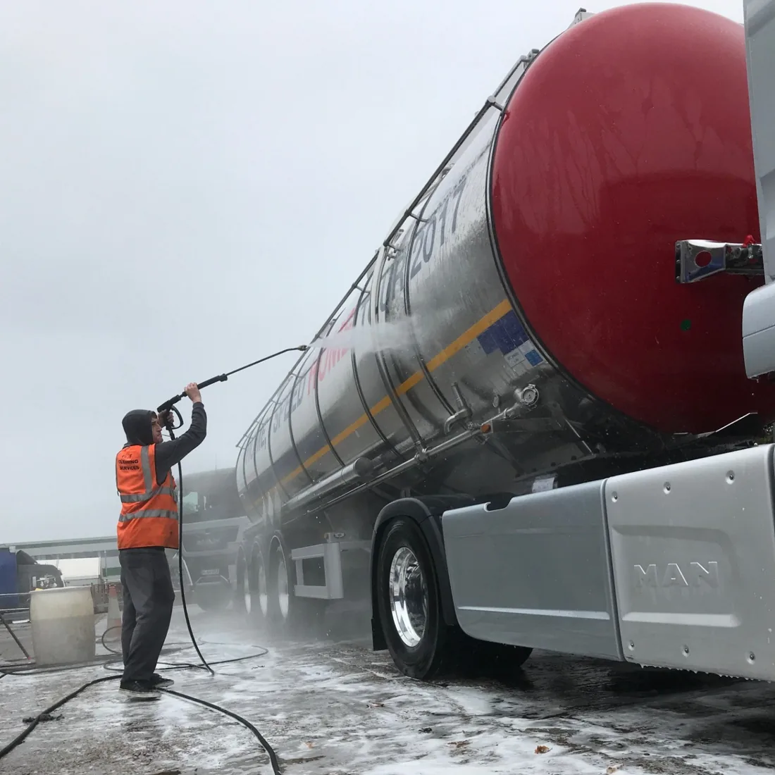 Worker pressure washing a tanker trailer